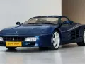 Niebieskie Ferrari 512 TR Spider z lat 90. błyszczy na wystawie, gotowe na przejażdżkę.