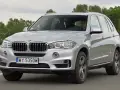 Srebrne BMW X5 E70 w ruchu. Kierowca za kierownicą. Rozpiska bezpieczników BMW X5 E70 jest kluczowa dla jego sprawnego działania.