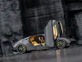 Szary Koenigsegg Gemera, czteromiejscny supersamochód z otwartymi drzwiami, prezentuje swoje żółte wnętrze na tle skalistej ściany.