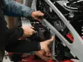 Mechanicy pracują nad motocyklem, być może rozwiązując problem zapchanego filtra paliwa powodującego szarpanie.