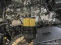 Wymiana oleju Hyundai Tucson 2.0 CRDi: nowy filtr oleju w ręku, gotowy do montażu. Silnik w tle.