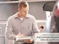 Mechanik z logo Audi na koszulce notuje szczegóły w dokumencie. Twój kompletny przewodnik po **Audi plan serwisowy**.