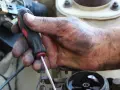 Brudna ręka mechanika z kluczem, naprawia coś w samochodzie. Może to być związane z linki skrzyni biegów objawy.