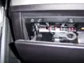 W schowku BMW E60 widać rząd bezpieczników i narzędzie do ich wyciągania.