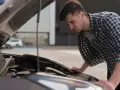Mężczyzna pochyla się nad otwartą maską Hyundaia i30, prawdopodobnie planując wymianę żarówki.