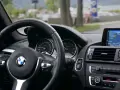 Wnętrze BMW z kierownicą i nawigacją. Kierowca sprawdza plan serwisowy przed podróżą.
