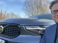 Mężczyzna w okularach i garniturze pozuje do zdjęcia z przodu Volvo XC40. Czy są jakieś wady tego modelu?