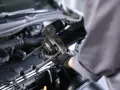 Mechanik w rękawiczkach trzyma rozrusznik na krótko, gotowy do montażu w silniku samochodu.