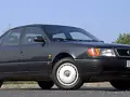 Klasyczny, ciemnoszary Audi A6 C4 z lat 90. stoi na tle błękitnego nieba i zieleni.