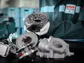 Mechanik w rękawiczkach prezentuje turbosprężarkę i jej elementy. Widać wirnik, obudowę i części mechanizmu sterującego, jak zawór N75 podłączenie.