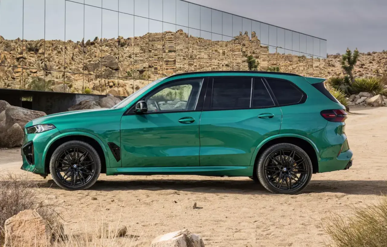 Zielony, sportowy SUV z czarnymi felgami, zaparkowany na pustyni. To ekonomiczne auto, które przyciąga wzrok.