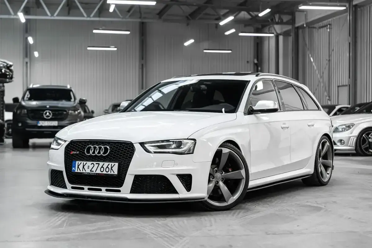 Białe Audi RS4 Avant z przyciemnianymi szybami i sportowymi felgami stoi w garażu.