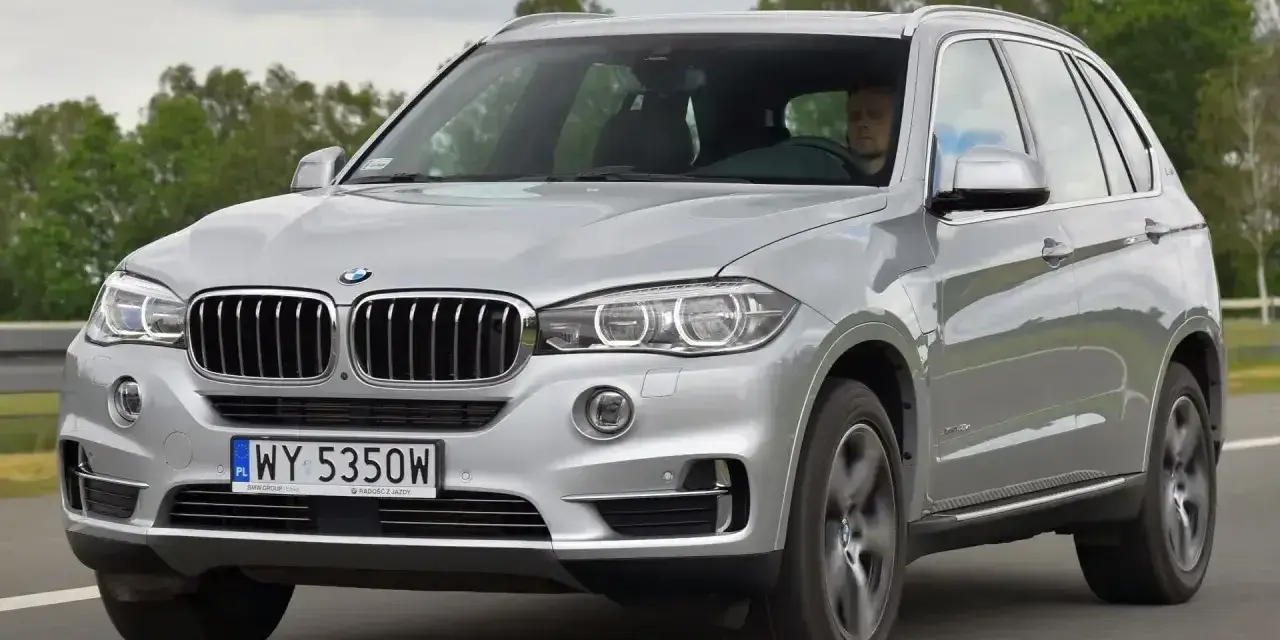 Srebrne BMW X5 E70 w ruchu. Kierowca za kierownicą. Rozpiska bezpieczników BMW X5 E70 jest kluczowa dla jego sprawnego działania.