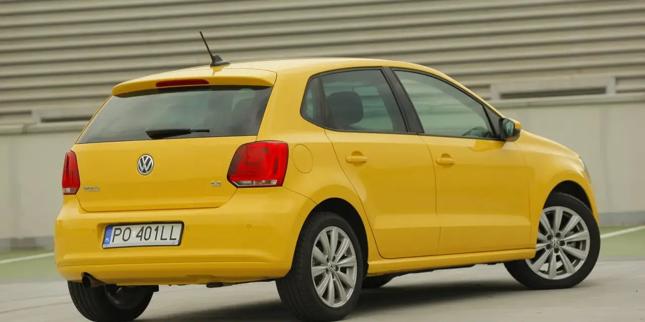 Żółty Volkswagen Polo widziany z tyłu, z widocznym tylnym światłem i tablicą rejestracyjną.