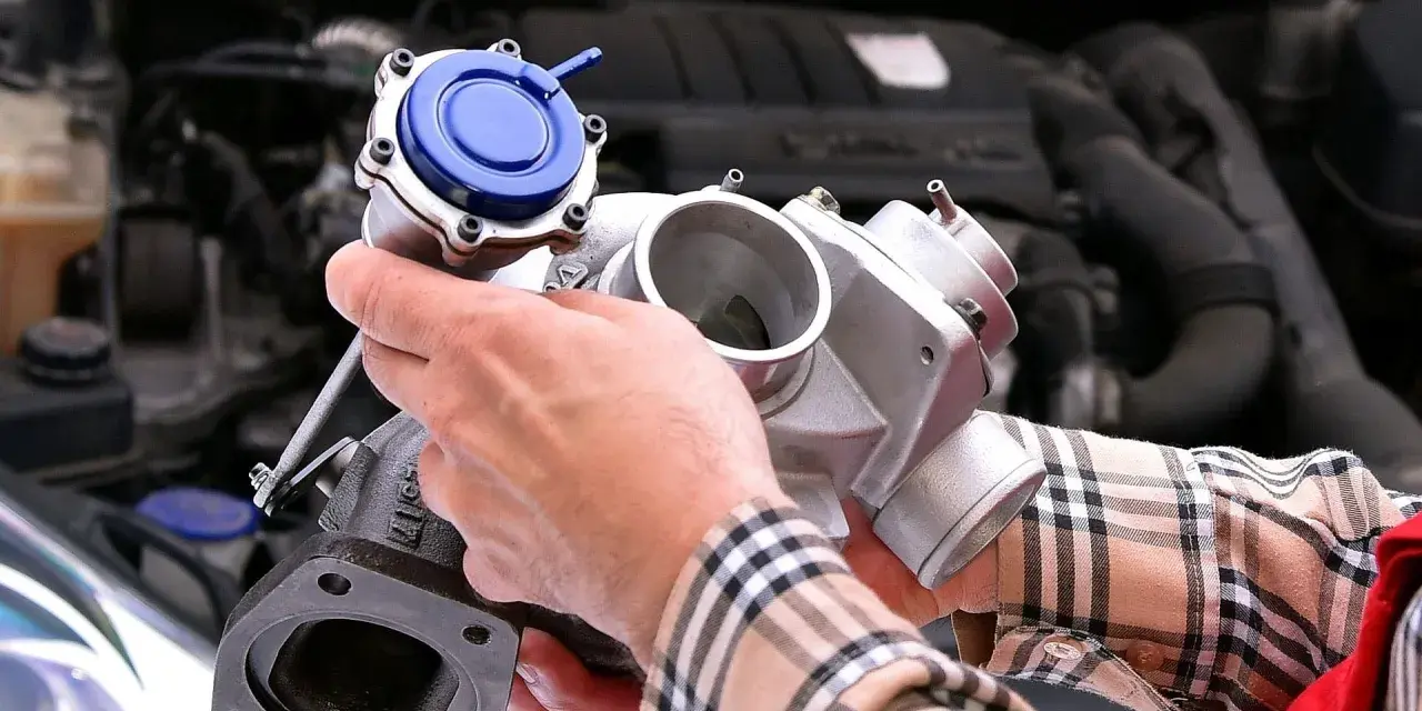 Mechanik trzyma turbosprężarkę, pokazując, gdzie znajduje się czujnik ciśnienia doładowania.