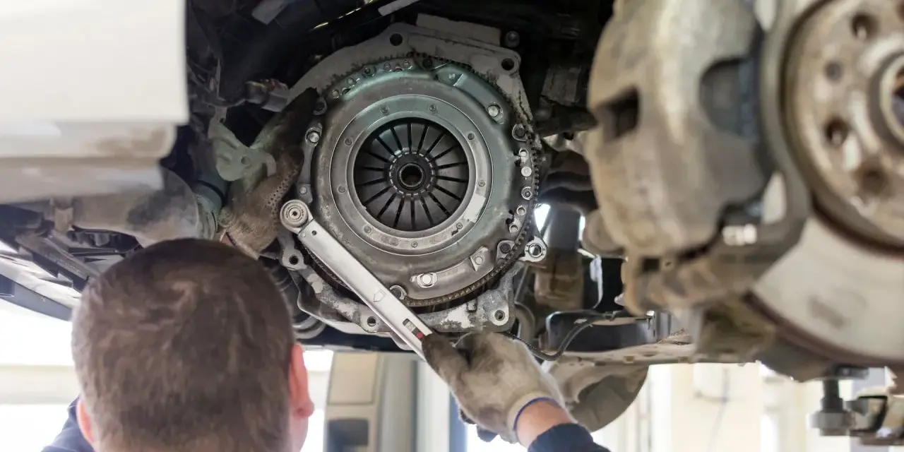 Mechanik dokręca śruby docisku sprzęgła. Wymiana sprzęgła krok po kroku w trakcie naprawy samochodu.