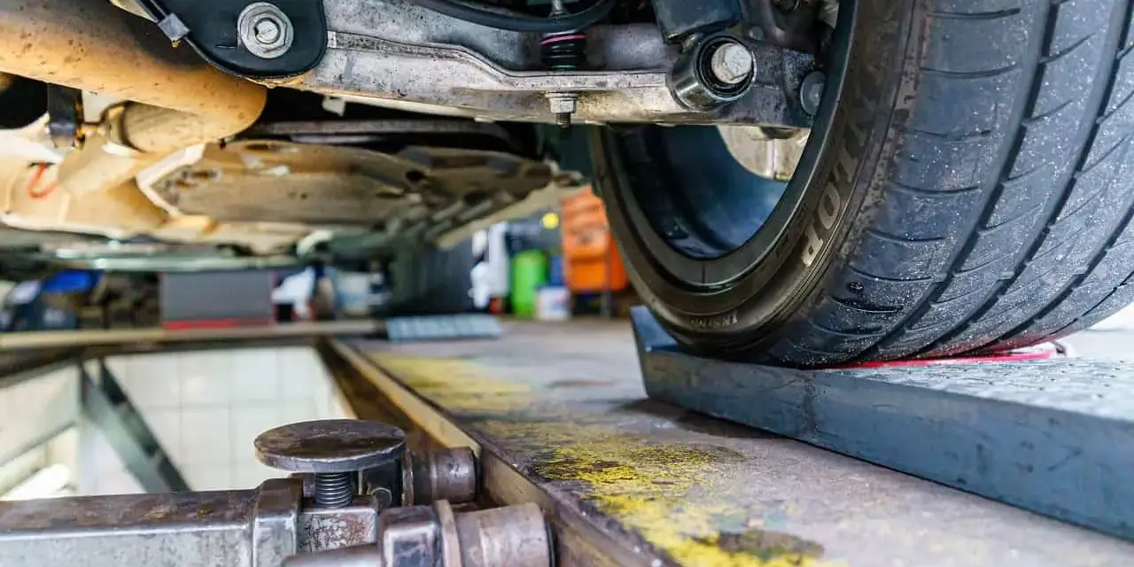 Podczas regulacji geometrii zawieszenia w warsztacie samochodowym, mechanik precyzyjnie ustawia kąty kół.