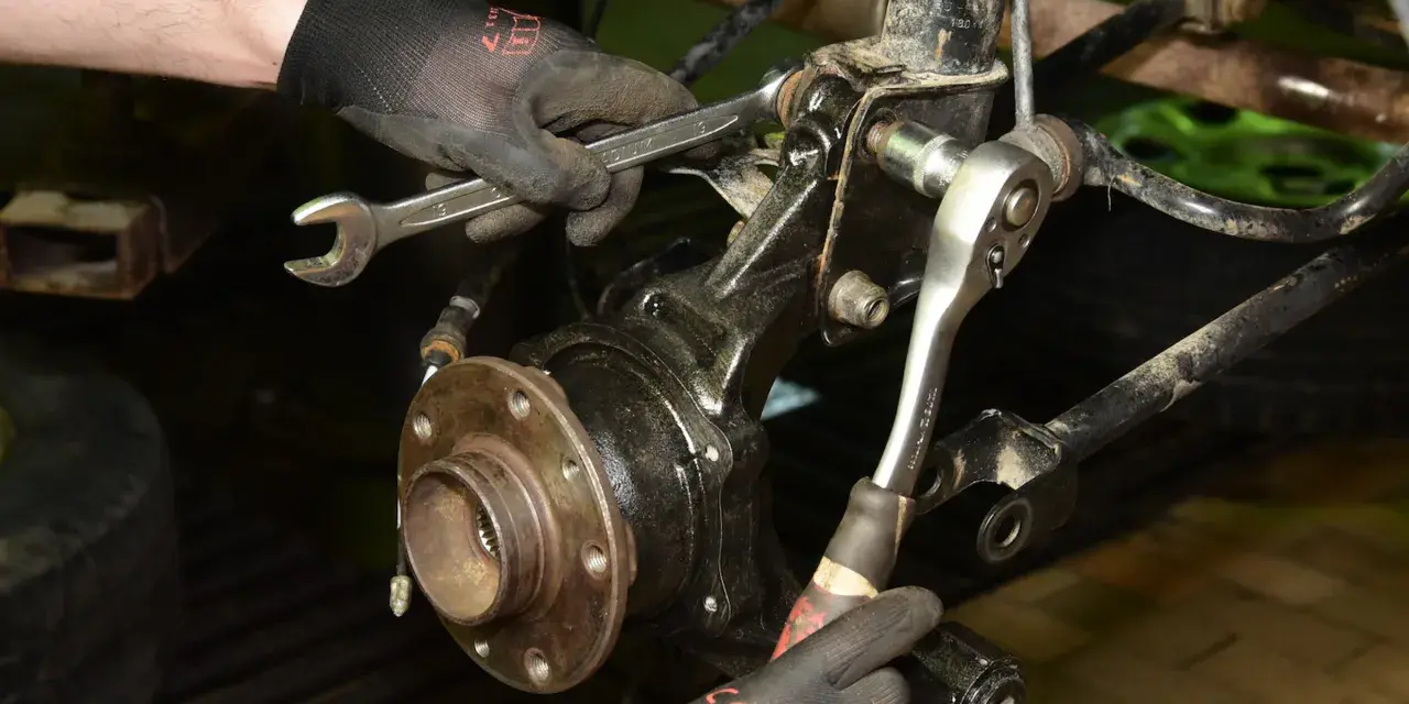 Mechanik wymienia łożysko w Audi A3 8P przód, używając kluczy do demontażu elementów zawieszenia.