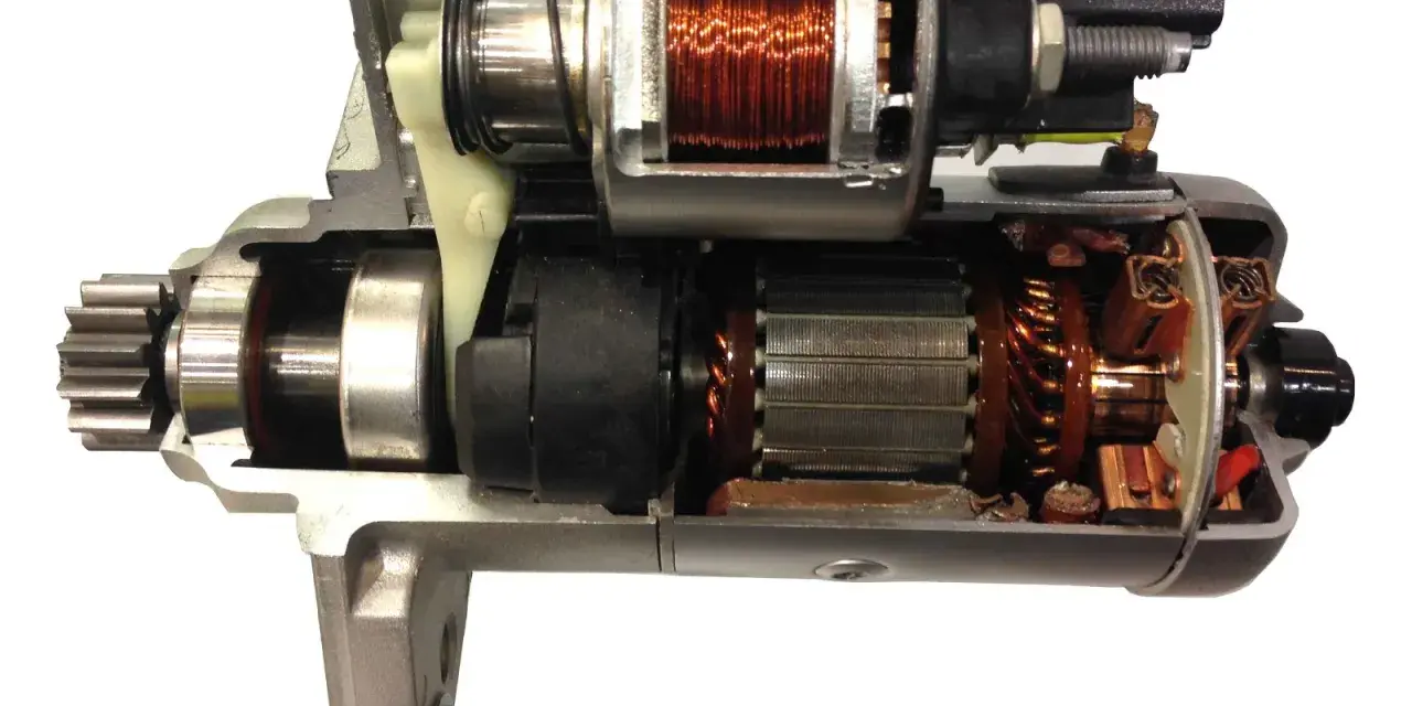 Przekrój rozrusznika samochodowego ukazuje jego wewnętrzną budowę: zębatkę, uzwojenia i mechanizm elektromagnetyczny.