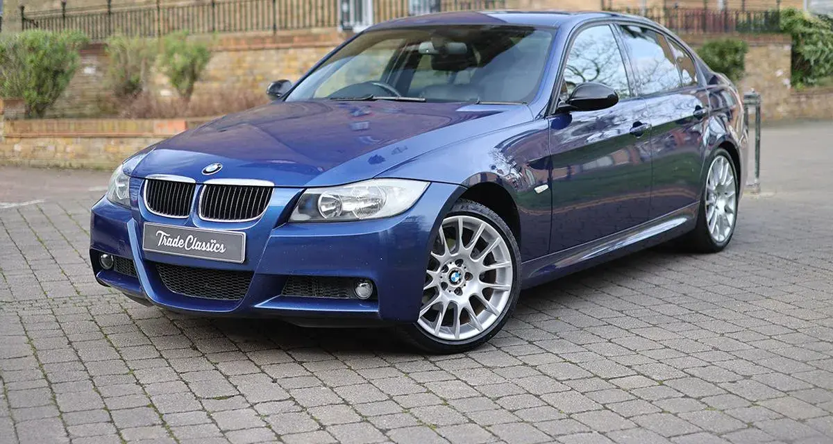 Błękitne BMW 320si z felgami M-pakietu stoi na brukowanym podjeździe.