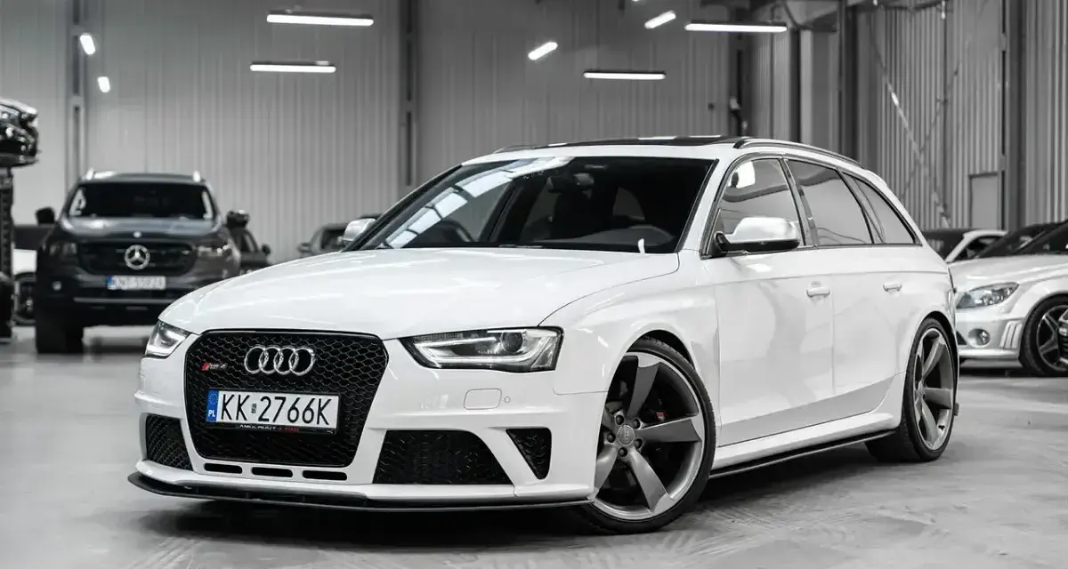 Białe Audi RS4 Avant z przyciemnianymi szybami i sportowymi felgami stoi w garażu.