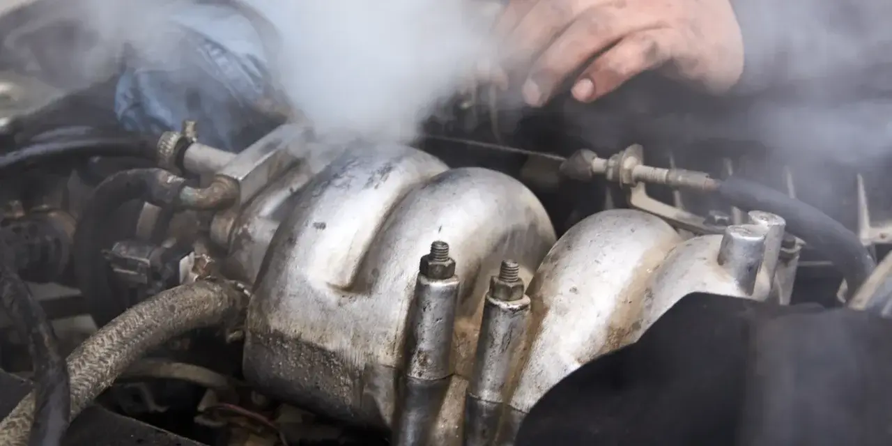 Para wylatuje z silnika. Czy można wlać płyn chłodniczy do ciepłego silnika? Mechanik sprawdza problem.
