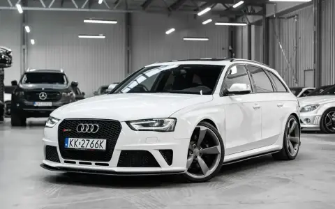 Białe Audi RS4 Avant z przyciemnianymi szybami i sportowymi felgami stoi w garażu.