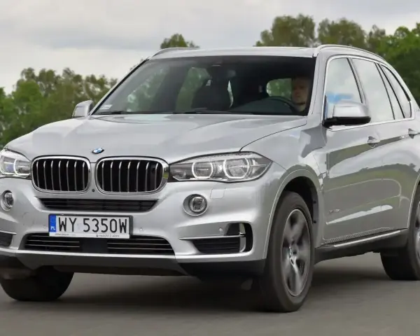 Srebrne BMW X5 E70 w ruchu. Kierowca za kierownicą. Rozpiska bezpieczników BMW X5 E70 jest kluczowa dla jego sprawnego działania.