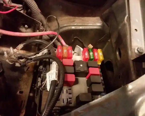 Skrzynka z bezpiecznikami w Fiat Doblo. Widać kolorowe bezpieczniki i przekaźniki.