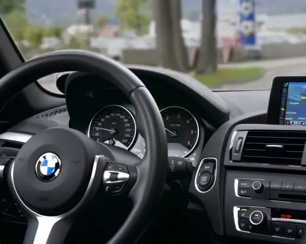 Wnętrze BMW z kierownicą i nawigacją. Kierowca sprawdza plan serwisowy przed podróżą.