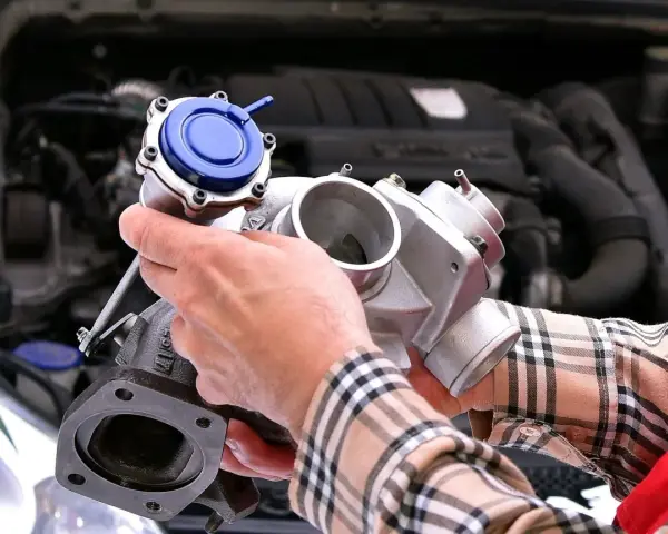 Mechanik trzyma turbosprężarkę, pokazując, gdzie znajduje się czujnik ciśnienia doładowania.