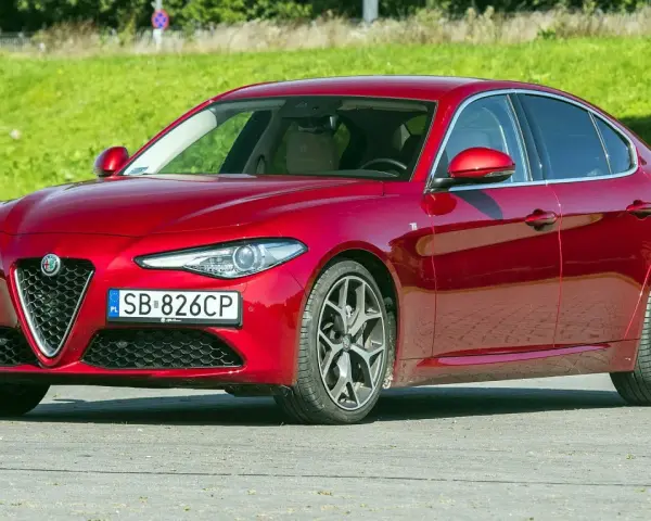 Czerwona Alfa Romeo Giulia, zgrabna sylwetka i mocne silniki, gotowa do jazdy.