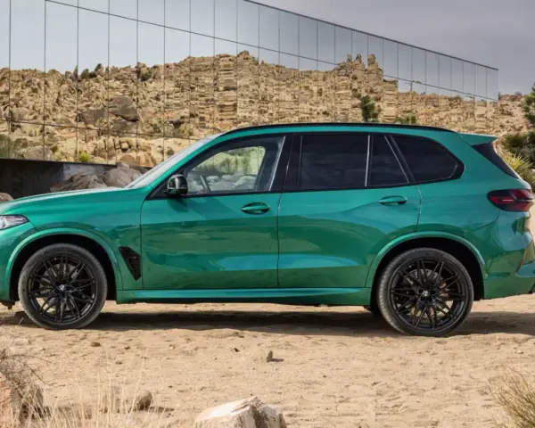 Zielony, sportowy SUV z czarnymi felgami, zaparkowany na pustyni. To ekonomiczne auto, które przyciąga wzrok.