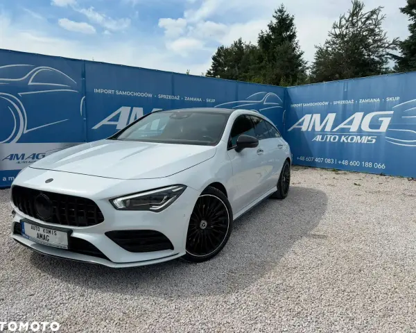 Biały Mercedes na tle niebieskiego banera AMAG Auto Komis. Idealny do akcje serwisowe Mercedes.