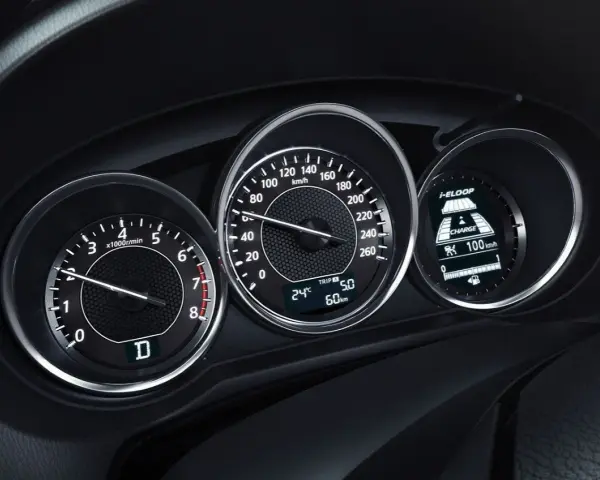 Zbliżenie na deskę rozdzielczą samochodu: obrotomierz pokazuje ok. 1500 obr./min, prędkościomierz ok. 60 km/h, a wyświetlacz i-ELOOP informuje o ładowaniu.