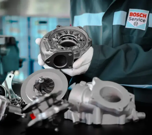 Mechanik w fartuchu Bosch Service prezentuje części turbosprężarki. Dowiedz się, jak jeździć dieslem, by cieszyć się jego mocą.