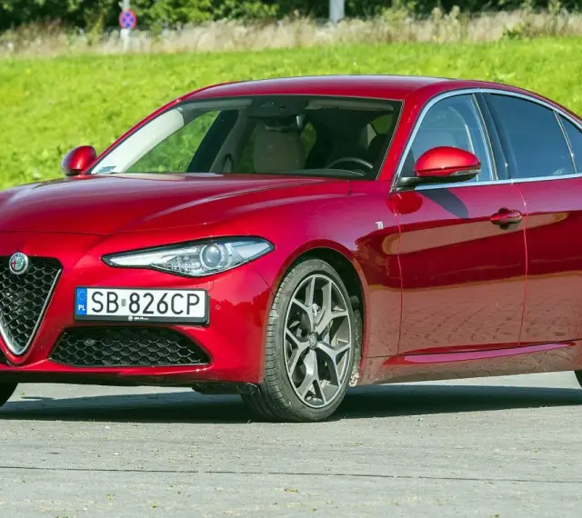 Czerwona Alfa Romeo Giulia, zgrabna sylwetka i mocne silniki, gotowa do jazdy.