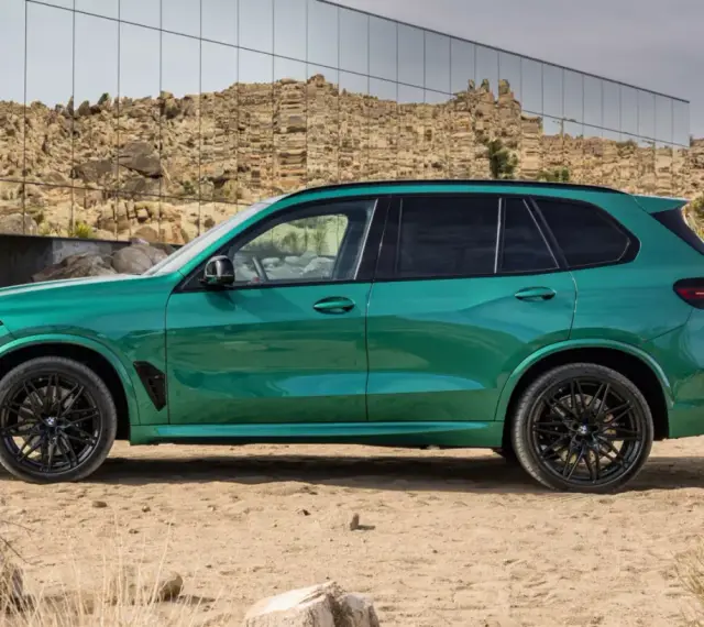Zielony, sportowy SUV z czarnymi felgami, zaparkowany na pustyni. To ekonomiczne auto, które przyciąga wzrok.