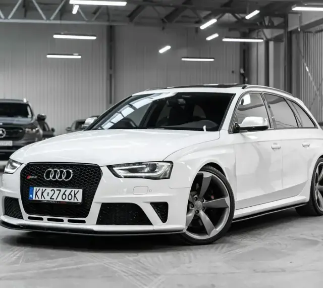 Białe Audi RS4 Avant z przyciemnianymi szybami i sportowymi felgami stoi w garażu.