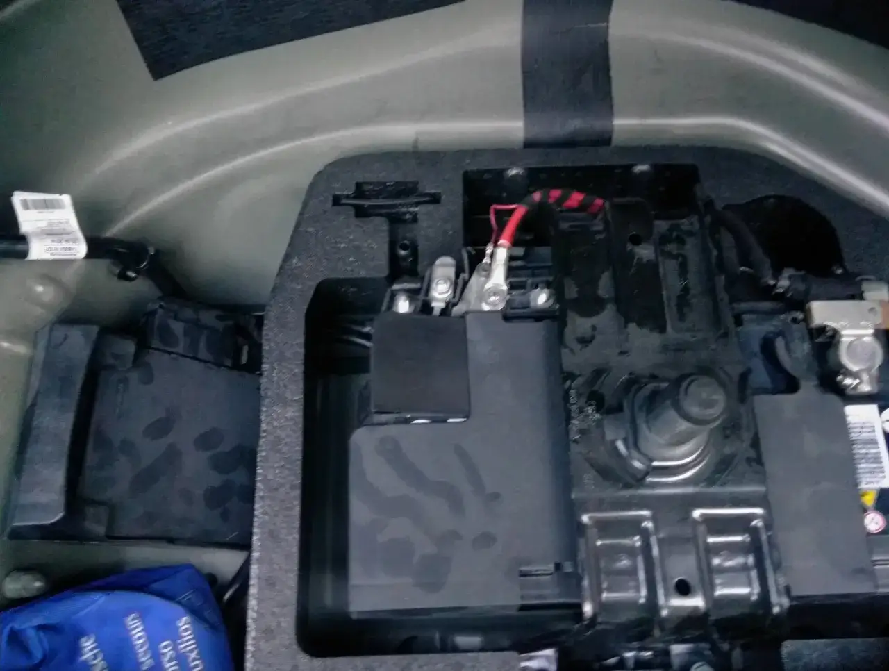 Audi A5 akumulator gdzie jest? W bagażniku, pod osłoną. Widoczne zaciski i przewody.