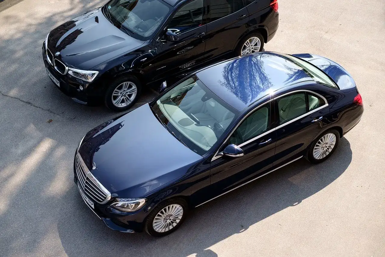 Dwa lśniące samochody: ciemnoniebieski Mercedes i czarny BMW. Zastanawiasz się, jaki jest ich rok modelowy a rok produkcji?