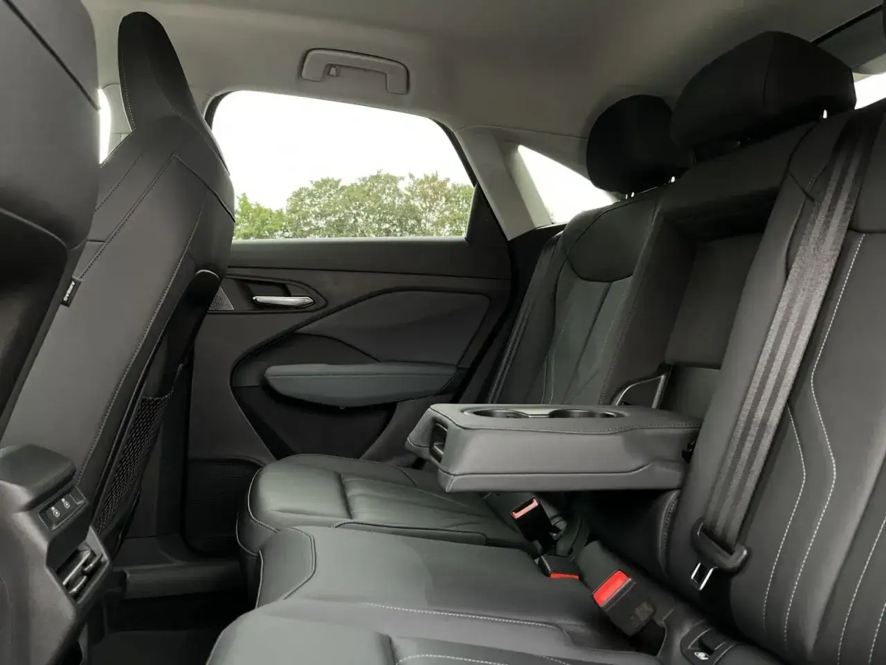 Wygodne, skórzane fotele i podłokietnik z uchwytami na napoje w audi q3 sportback wnętrze.