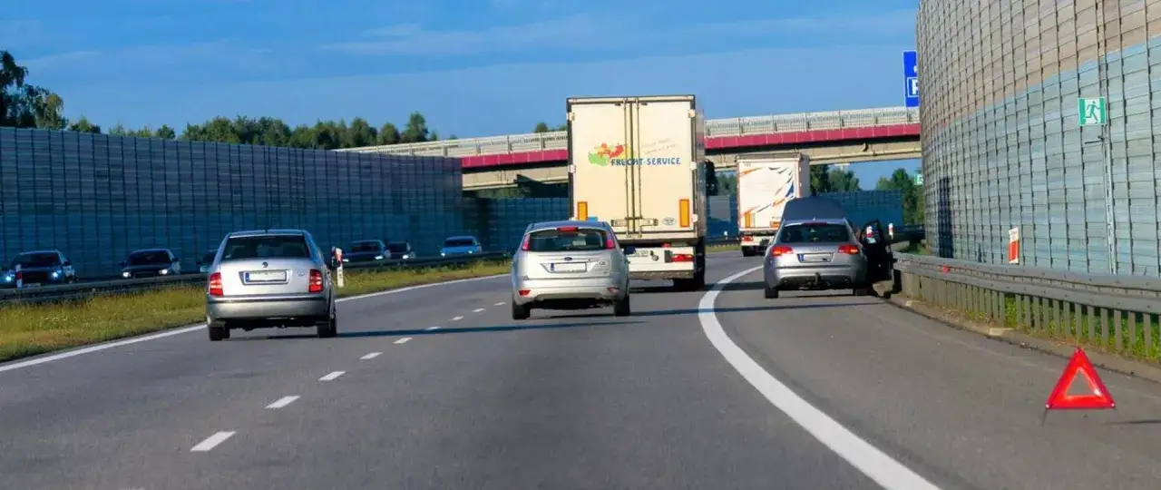 Na drodze ekspresowej jednojezdniowej samochód z otwartą maską i trójkątem ostrzegawczym.
