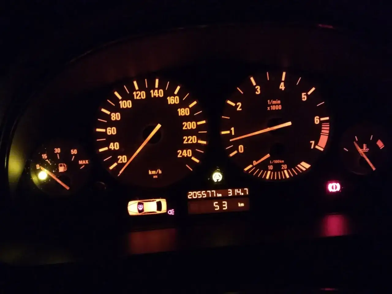 Deska rozdzielcza BMW: prędkościomierz pokazuje ok. 50 km/h, obrotomierz ok. 1500 obr./min. Wskaźnik paliwa niski. Stabilizacja toru jazdy działa, jedź wolno.