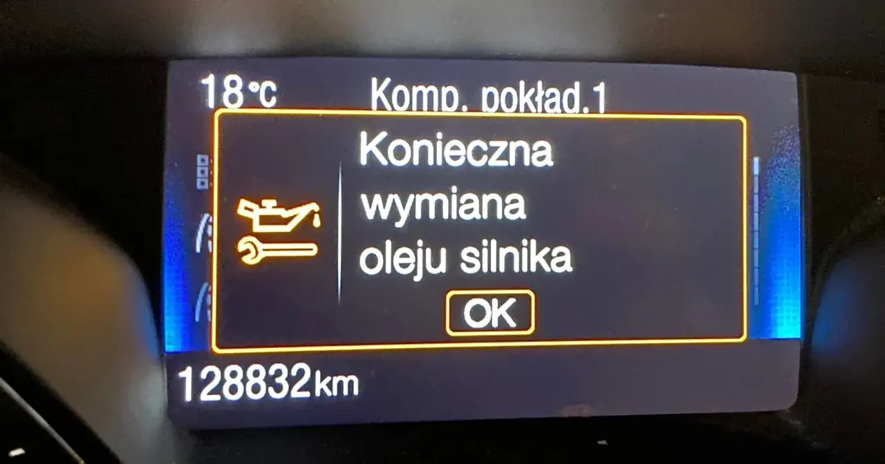 Na wyświetlaczu samochodu: 18°C, Komputer pokładowy. Konieczna wymiana oleju silnika. Przebieg 128832 km.