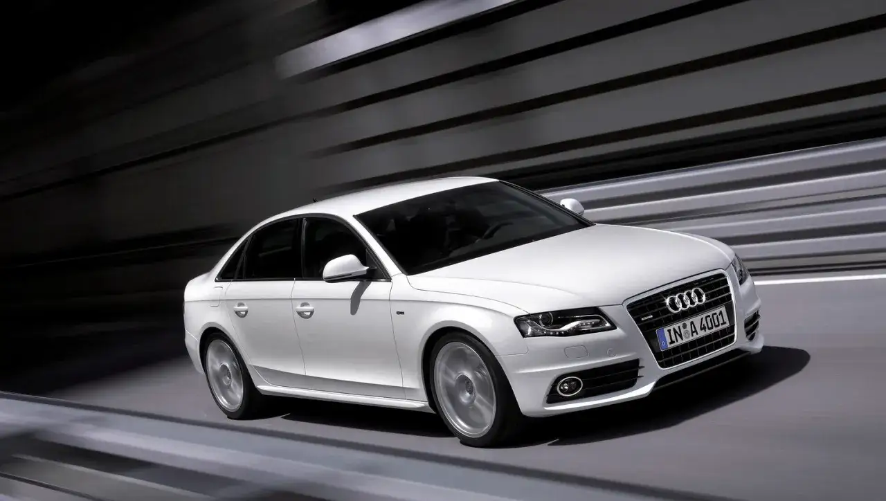 Białe Audi A4 B8 w ruchu, z widocznymi typowymi usterkami tego modelu, jak np. problemy z napędem quattro.