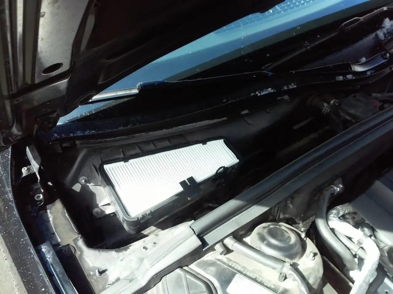 Wymiana filtra kabinowego Audi A4 B8. Nowy, biały filtr czeka na montaż w komorze silnika.
