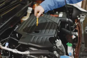 Mechanik sprawdza poziom oleju w silniku Peugeot 508. Wymiana oleju w skrzyni manualnej to ważny element dbania o auto.