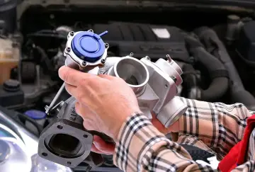 Mechanik trzyma turbosprężarkę, pokazując, gdzie znajduje się czujnik ciśnienia doładowania.