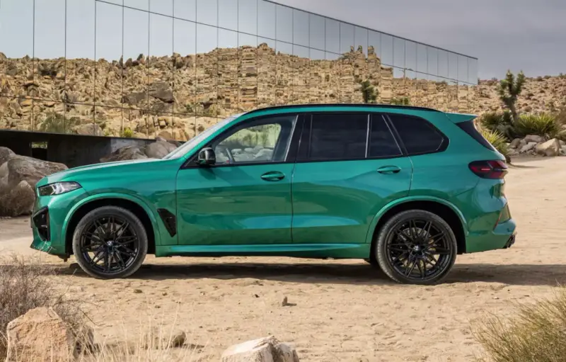 Zielony, sportowy SUV z czarnymi felgami, zaparkowany na pustyni. To ekonomiczne auto, które przyciąga wzrok.